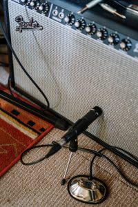 Close-up of a microphone and amplifier setup in a cozy home music studio.